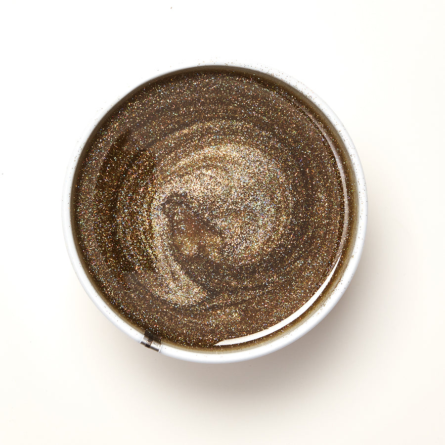 Round metallic container with glitter wax on a white background