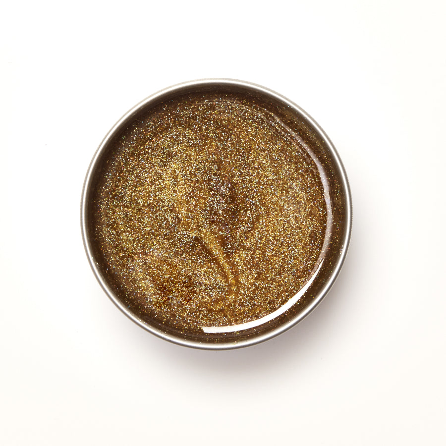 Round metallic container with glitter wax on a white background
