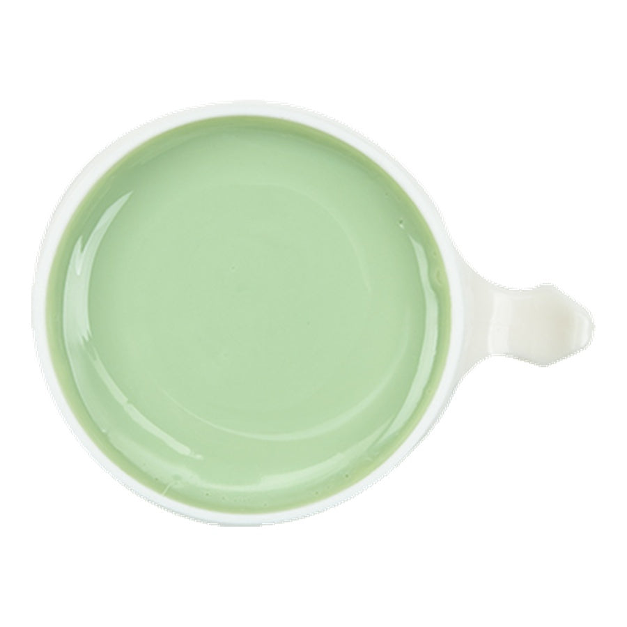 Green liquid in a white mug on a white background